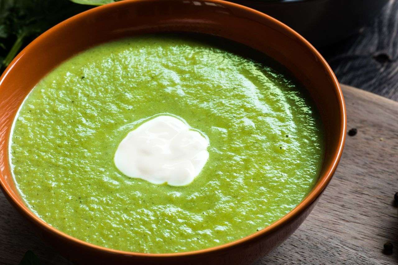 Cremige grüne Spinatsuppe in eine, braunen Suppenteller mit Sahneklecks