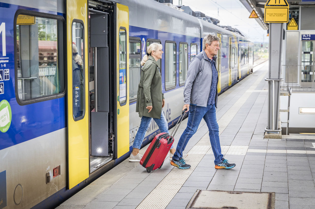 Zug der DB hält am Bahnsteig und Fahrgäste steigen aus